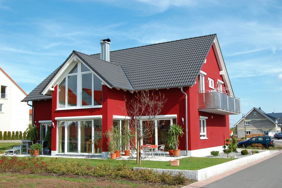 Modernes Einfamilienhaus mit Garten und Balkon Modernes rotes Einfamilienhaus mit Garten, Terrasse und Balkon an einem sonnigen Tag.