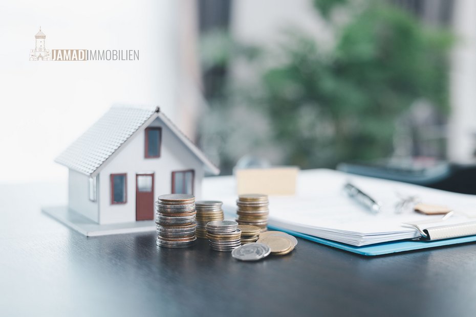 Immobilienwert und Finanzierung im Blick Kleines Modellhaus neben aufgestapelten Münzen und Unterlagen – Symbol für Immobilienfinanzierung und Wertermittlung.